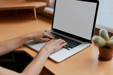Masada çalışıyor, onun beyaz dizüstü bilgisayarda yazarak kadın.