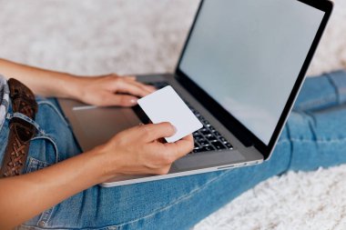 Kredi kartı tutan ve bir dizüstü bilgisayarda web, arama bilgi tarama, evde çalışma alanı olan yere, ödeme, oturma bir dizüstü bilgisayar kullanarak erkek çalışan kadın. Bloglama kavramını. Modern teknolojiler. Üstten Görünüm.