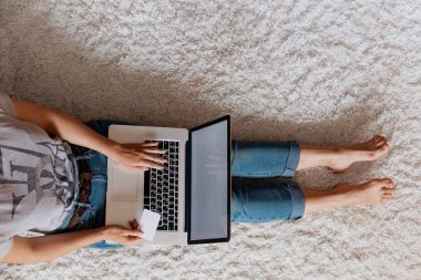 Shoping online, ödeme, kredi kartı tutan ve bir dizüstü bilgisayarda web, arama bilgi tarama, evde çalışma alanı olan yere, oturma bir dizüstü bilgisayar kullanarak erkek çalışan kadın. Bloglama kavramını. Modern teknolojiler. Üstten Görünüm.
