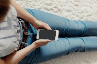 Kredi kartı tutan ve telefonunuzun ve katta oturan genç kadın. Ödeme. Online alışveriş kavramı. Bloglama kavramını. Modern teknolojiler Üstten Görünüm.