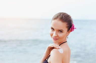 Kadın tabaklanmış omzuna güneş koruyucu krem uygulamak. Cilt Bakımı. Güneşten korunma. Kız kullanma güneş kremi losyon arka