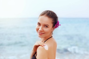 Kadın tabaklanmış omzuna güneş koruyucu krem uygulamak. Cilt Bakımı. Güneşten korunma. Kız kullanma güneş kremi losyon arka