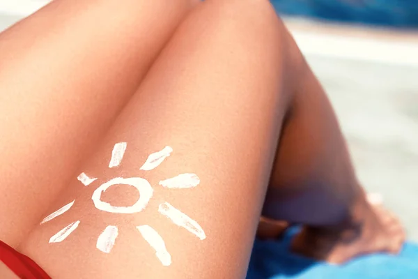 Portrait of gorgeous woman in bikini with the drawn sun on a leg.Sunscream