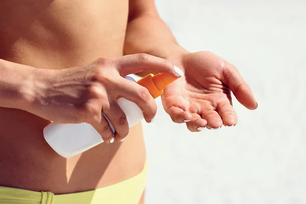 Suntan lotion. Woman applying sunscreen solar cream. Beautiful happy cute woman applying suntan cream from a plastic bottle to her hand.