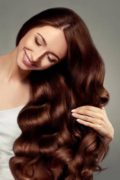 Saç. Uzun dalgalı ve parlak saçlı güzel kız. Muhteşem kıvırcık saç modeli ile Esmer kadın. Haircare. Sağlıklı uzun saçlar. Güzellik Model Kadın. Kahverengi Saç. 
