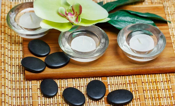 Beautiful spa and wellness setting composition on massage table in relax center on blackboard with copy space.Towel, Salt, Plumeria Flower, Hot stones Bowl for spa therapy.Spa  products