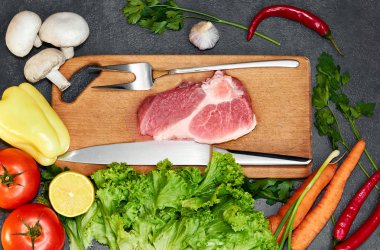 Taze sığır biftek, tahta kaşık, Taze Sebze Çeşitleri, aromatik otlar, baharat ve sebze pişirmek için , siyah arka plan, üst görünümü. Et