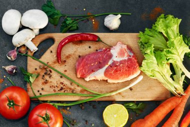 Taze sığır biftek, tahta kaşık, Taze Sebze Çeşitleri, aromatik otlar, baharat ve sebze pişirmek için , siyah arka plan, üst görünümü. Et