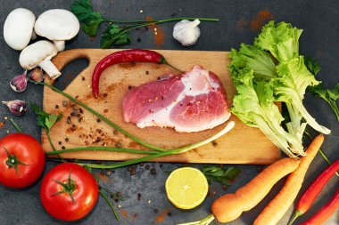 Taze sığır biftek, tahta kaşık, Taze Sebze Çeşitleri, aromatik otlar, baharat ve sebze pişirmek için , siyah arka plan, üst görünümü. Et