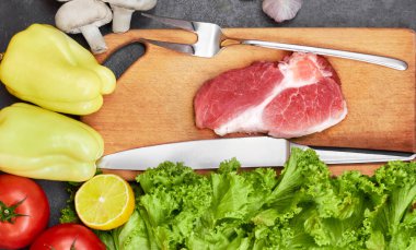 Taze sığır biftek, tahta kaşık, bıçak ve Taze Sebze Çeşitleri, aromatik otlar, baharatlar ve pişirme için sebze , rustik arka plan, üst görünüm, çerçeve.