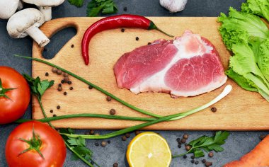 Taze sığır biftek, tahta kaşık, Taze Sebze Çeşitleri, aromatik otlar, baharat ve sebze pişirmek için , siyah arka plan, üst görünümü.