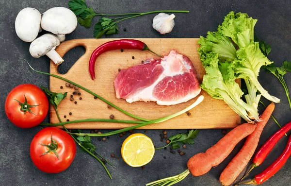 Taze sığır biftek, tahta kaşık, Taze Sebze Çeşitleri, aromatik otlar, baharat ve sebze pişirmek için , siyah arka plan, üst görünümü. Et