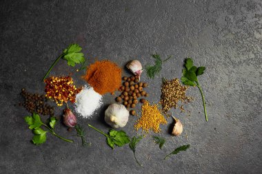 Baharat seçimi, siyah taş masada otlarl. Yemek pişirmek için malzemeler. Yemek geçmişi. Kopyalama alanı ile üstte görünüm.