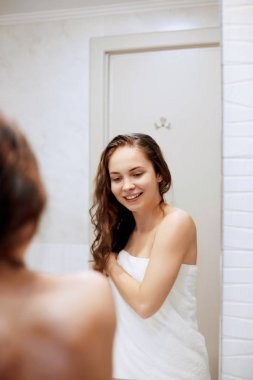 Güzel genç kadın elleriyle ıslak saçlarına dokunup gülümsüyor