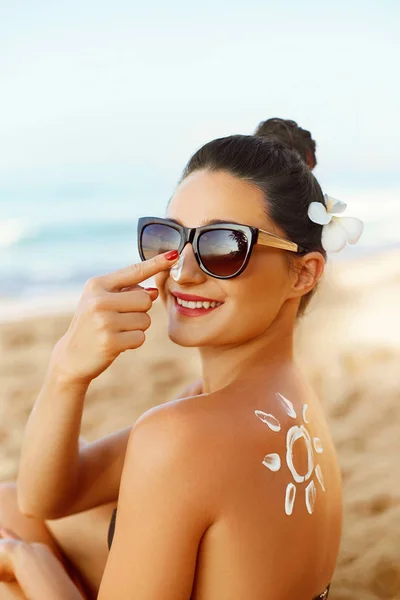 Suntan Lotion. Sexy Young Woman in Bikini  Applying Sunscreen Solar Cream.Sun Protection. Sun Cream. Skin and Body Care.Girl Holding Moisturizing Sunblock. Sun shape on the shoulder. Skin Protection