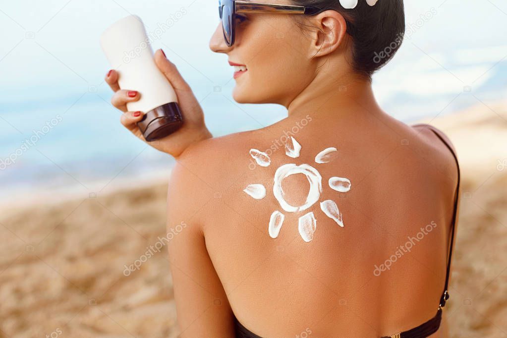 Skin care. Sun protection. Woman apply sun cream. Girl Holding Moisturizing Sunblock. Woman With Suntan Lotion On Beach In Form Of The Sun. Portrait Of Female With  Drawn Sun On A Shoulder. Suncream.