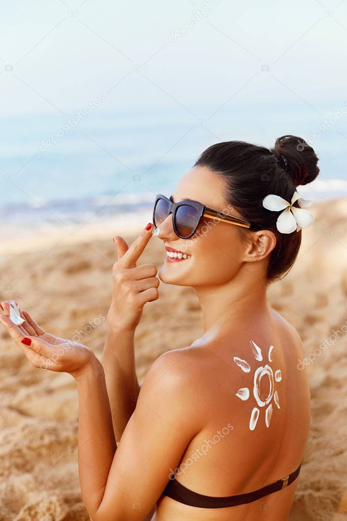 Sun shape created from sunscreen lotion on young woman's back. Skin protection.Skin and Body Care.Facial  treatment. Sun Cream Safety sunbathing concept. Copy space