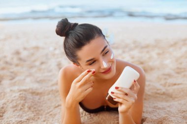 Cilt bakımı. Güneş koruması. Bikini güzel kadın Yüz güneş kremi uygulayın. Sahilde Suntan Losyonu olan kadın. Kadın Holding Nemlendirici Sunblock.The Girl Portresi Cildi için Güneş Kremi Kullanır. 