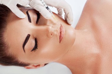 güzel genç kadın yüz ve eldiven elleri güzellik tedavisi enjeksiyon beyaz izole ile. Yüz enjeksiyonu. Kadın dudaklarda kozmetik enjeksiyon alma, closeup.