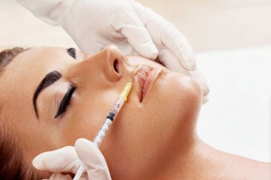 Kadının dudaklarına kozmetik iğne yapılıyor. Yakın plan. Güzellik salonundaki kız. Estetik cerrahi kliniği.