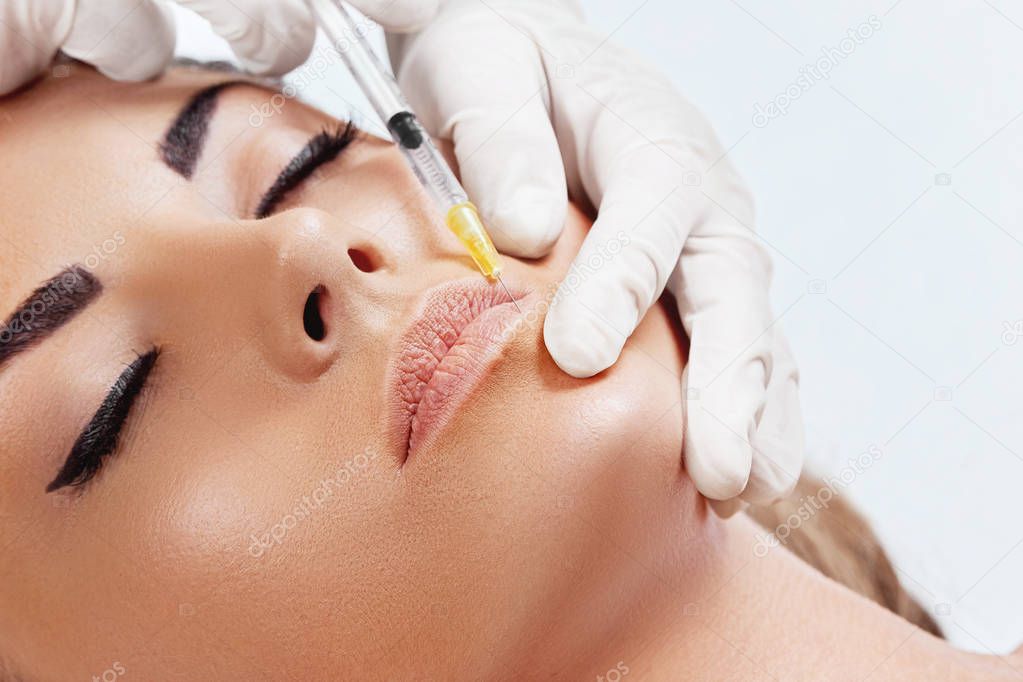 Beautiful woman getting cosmetic injection of botox in lips, Plastic surgery, beauty concept. Closeup hand in glove with syringe making injection. Girl in beauty salon.Hyaluronic Collagen Injection.Facelift