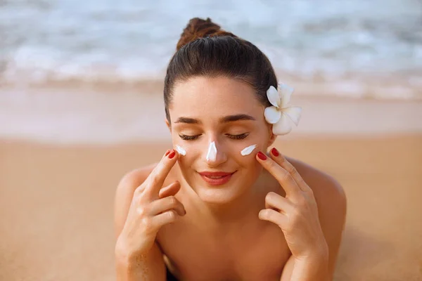 Beautiful Woman Face Portrait Beauty Skin Care Concept. Suncream. Suntan Lotion Beautiful Woman Applying on beautifu on Face. Sunscreen Solar Cream. Sun protection.The Girl Uses  Moisturizer Sunblock