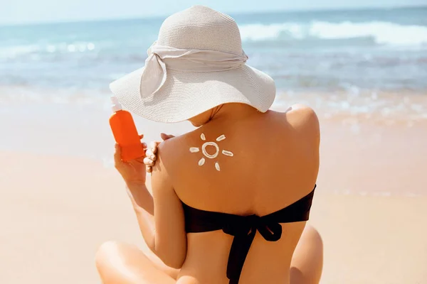 Suncream. Suntan Lotion Beautiful Woman Applying on beautiful on Shoulder In Form Of The Sun. Sunscreen Solar Cream. Skin care. Sun protection.The Girl Uses  Moisturizer Sunblock