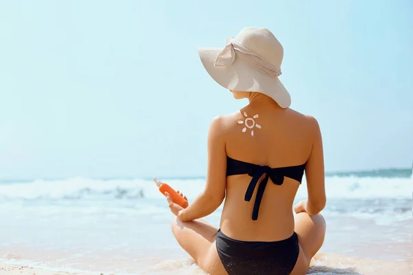 Sun cream on tanned shoulder with sun shape . Sun protection. Beautiful woman in bikini applying  Solar Cream. Skin and body care.Portrait of female holding suntan lotion and moisturizing sunblock.