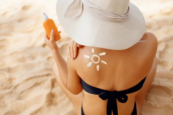Beauty Woman putting sunblock lotion on shoulder before tanning during summer holiday on beach vacation resort