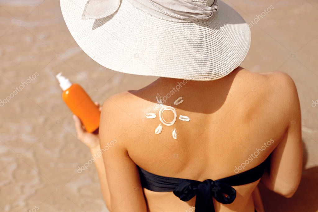Skin care.Sun protection. Beautiful Woman In Bikini apply sun cream on Face. Woman With Suntan Lotion On Beach. Portrait Of Female Holding Moisturizing Sunblock. The Girl Uses Sunscreen for Her Skin.