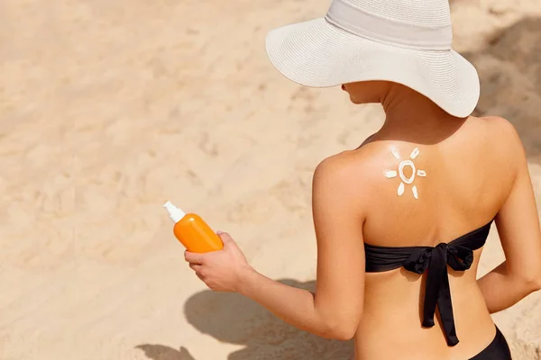 Skin care. Sun protection. Beautiful Woman apply sun cream on Face. Woman With Suntan Lotion On Beach. Portrait Of Female Holding Moisturizing Sunblock. The Girl Uses Sunscreen for Her Skin.