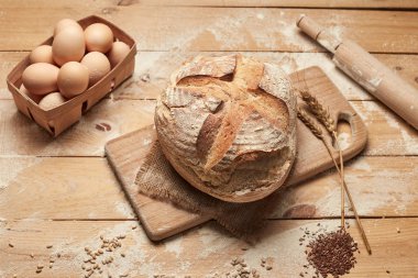 Ekmek fırın altın rustik kabuklu somun ve ahşap arka plan üzerinde. Yukarıdan yakalanan natürmort (üstte, düz yatıyordu).