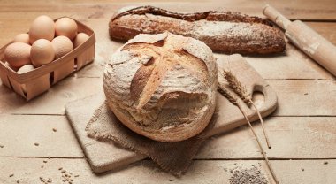 Ekmek fırın altın rustik kabuklu somun ve ahşap arka plan üzerinde. Yukarıdan yakalanan natürmort (üstte, düz yatıyordu).