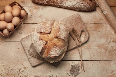 Ekmek fırın altın rustik kabuklu somun ve ahşap arka plan üzerinde. Yukarıdan yakalanan natürmort (üstte, düz yatıyordu).