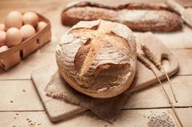 Ekmek fırın altın rustik kabuklu somun ve ahşap arka plan üzerinde. Yukarıdan yakalanan natürmort (üstte, düz yatıyordu).