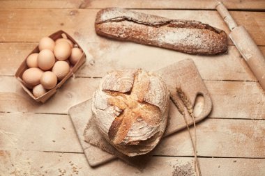 Ekmek fırın altın rustik kabuklu somun ve ahşap arka plan üzerinde. Yukarıdan yakalanan natürmort (üstte, düz yatıyordu).
