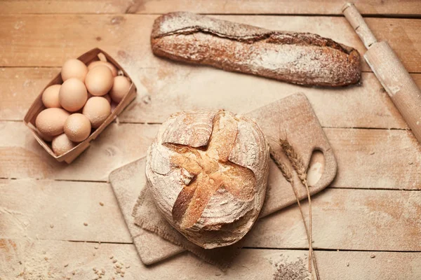 Ekmek fırın altın rustik kabuklu somun ve ahşap arka plan üzerinde. Yukarıdan yakalanan natürmort (üstte, düz yatıyordu).