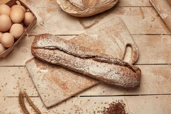 Ekmek fırın altın rustik kabuklu somun ve ahşap arka plan üzerinde. Yukarıdan yakalanan natürmort (üstte, düz yatıyordu).
