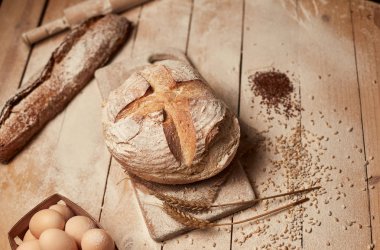 Ekmek fırın altın rustik kabuklu somun ve ahşap arka plan üzerinde. Yukarıdan yakalanan natürmort (üstte, düz yatıyordu).