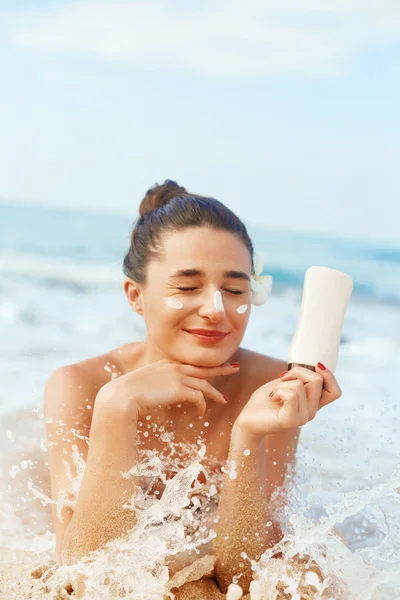 Suntan Lotion. Sexy Young Woman in Bikini  Applying Sunscreen Solar Cream.Sun Protection. Sun Cream. Skin and Body Care.Girl Holding Moisturizing Sunblock. Sun shape on the shoulder. Skin Protection