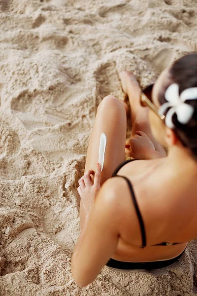 Closeup on female hand applying sunscreen creme on beautiful legs. Skincare. Suntan Lotion. Solar Cream. Sun protection sun cream, on her smooth tanned legs.