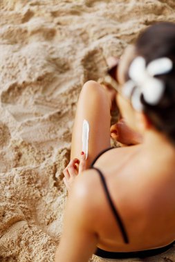 Güzel bacaklar üzerinde güneş kremi uygulayarak kadın elinde Closeup. Skincare. Suntan Losyonu. Güneş kremi. Güneş koruma güneş kremi, onu pürüzsüz tabaklanmış bacaklarda.
