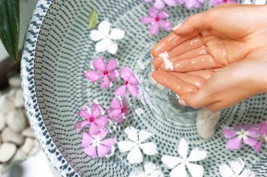 Tırnaklar ve su ve çiçek ile kase üzerinde doğal manikür ile Genç kız Eller. Spa tedavisi ve kadın elleri için masaj. Yakından kapatın. Spa cilt ve vücut tırnakları bakım konsepti. Kozmetoloji