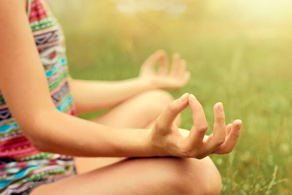 Hand of a woman meditating in lotus position practicing yoga in summer.Active Lifestyle. Healthy and yoga concept. Fitness and sports 