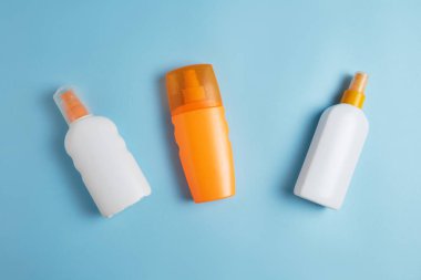 Güneş kremi, Güneş şapkası, krem, havlu, güneşlik şişesi, Güneş kremi, losyon şişesi, mavi arka planda güneş gözlüğü deniz kabuğu. Güneş koruması. Plaj düz aksesuarlar yatıyordu. Yaz seyahati tatil konsepti. Summertime tatil