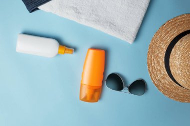 Güneş kremi, Güneş şapkası, krem, güneşlik şişesi, Güneş kremi, losyon şişesi, mavi arka planda güneş gözlüğü. Güneş koruması. Plaj düz aksesuarlar yatıyordu. Yaz seyahati tatil konsepti. Summertime tatil