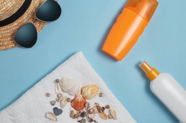 Güneş kremi, Güneş şapkası, krem, güneşlik şişesi, Güneş kremi, losyon şişesi, mavi arka planda güneş gözlüğü. Güneş koruması. Plaj düz aksesuarlar yatıyordu. Yaz seyahati tatil konsepti. Summertime tatil