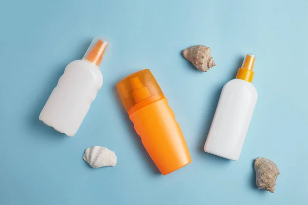 Sunscreen bottle,  sun hat, cream, lotion bottle, various sunscreens and seashells on a blue background. summer. vacation. Sun protection. top view