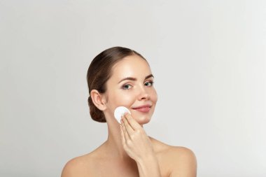 Sağlıklı taze kız ile pamuk yastık yüzü makyaj kaldırılıyor. Güzellik kadın yüzünü pamuk bez ile temizlik yastık üzerinde izole gri arka plan. Cilt bakım ve güzellik kavramı.