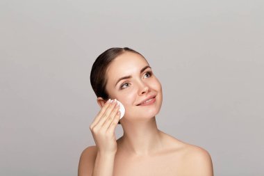 Woman Cleaning Face With White Pad. Beautiful Girl Removing Makeup White Cosmetic Cotton Pad. Happy Smiling Female Taking Off Makeup From Facial Skin With Cosmetic Pad. Face Skin Care. clipart